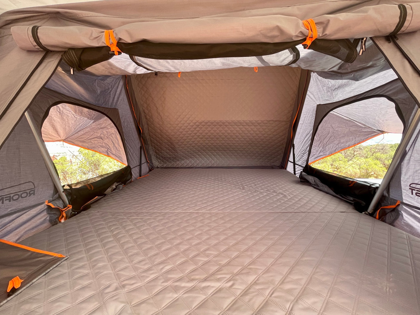 arid landscape.|White Jeep Gladiator overland vehicle with rooftop tent in red rock canyons. Perfect for your adventurous RV rental trip!|This white Jeep Gladiator **RV rental** with a rooftop tent overlooks a scenic valley from a desert cliff