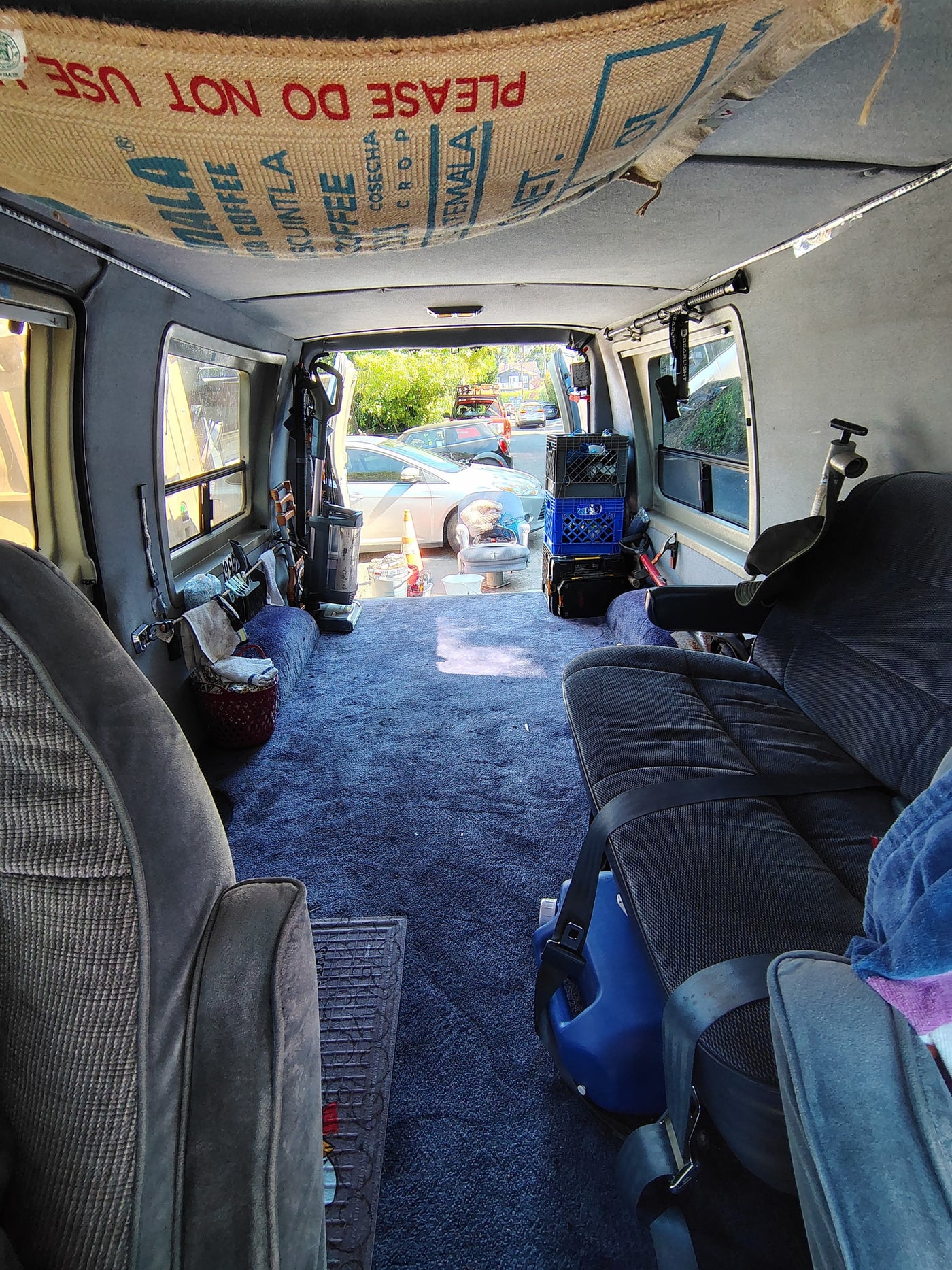 Explore this unique rv rental: a van interior featuring a coffee sack ceiling, blue carpet, and organized storage for adventures. — photo 2