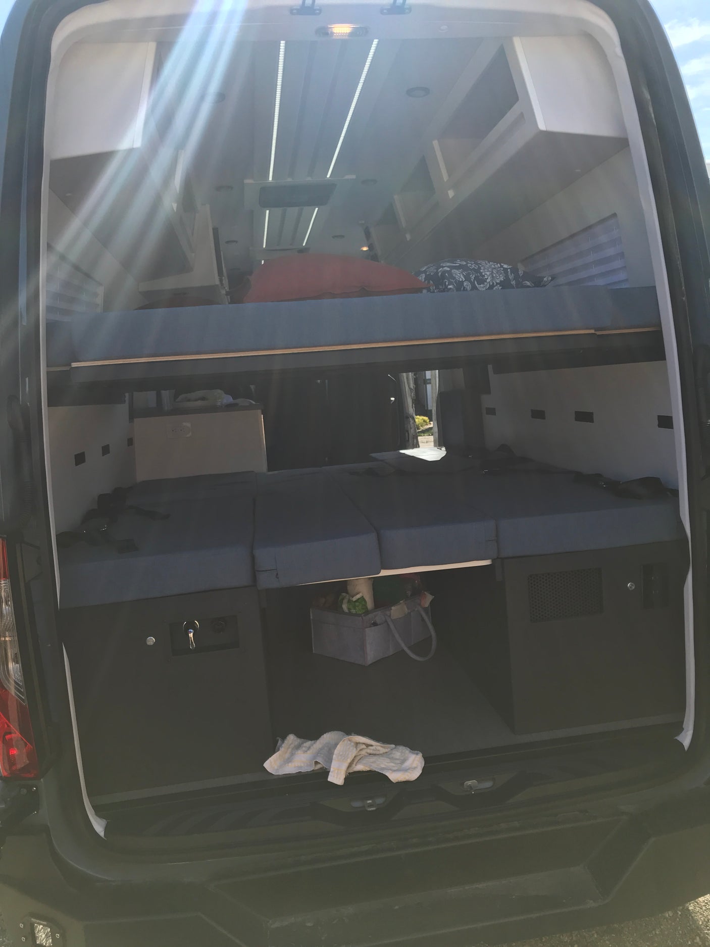Interior of an **rv rental** camper van: bunk beds, lower seating/sleeping cushions, and integrated storage units.