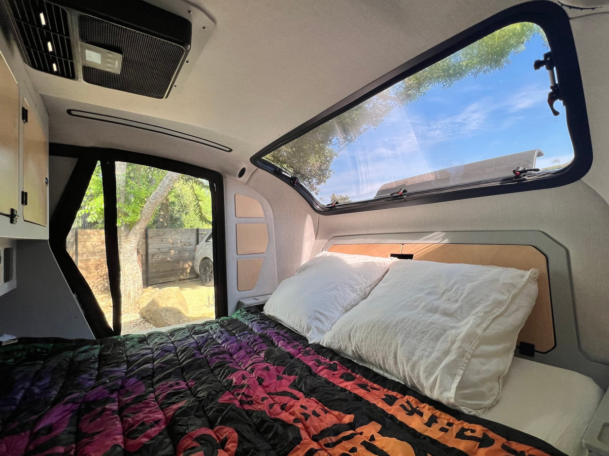 ready for off-grid adventures.|Rugged RV rental: close-up of its large off-road tire & suspension. Vehicle parked on wet pavement by a wooden fence & bike.|Compact kitchen setup in an RV rental — photo 12