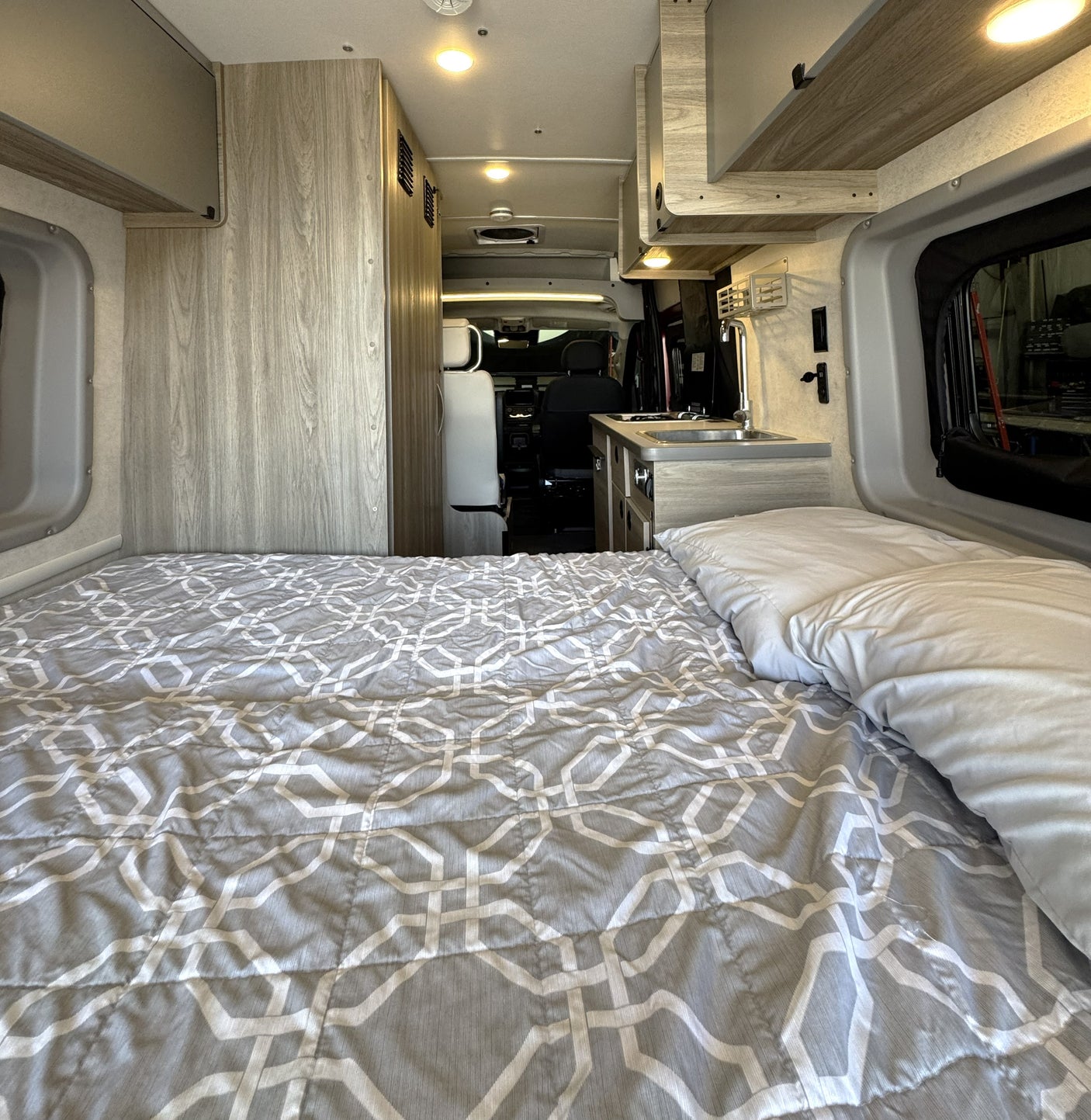 Cozy RV rental interior with a comfy bed, kitchenette, and bright lighting, perfect for your next road trip adventures.
