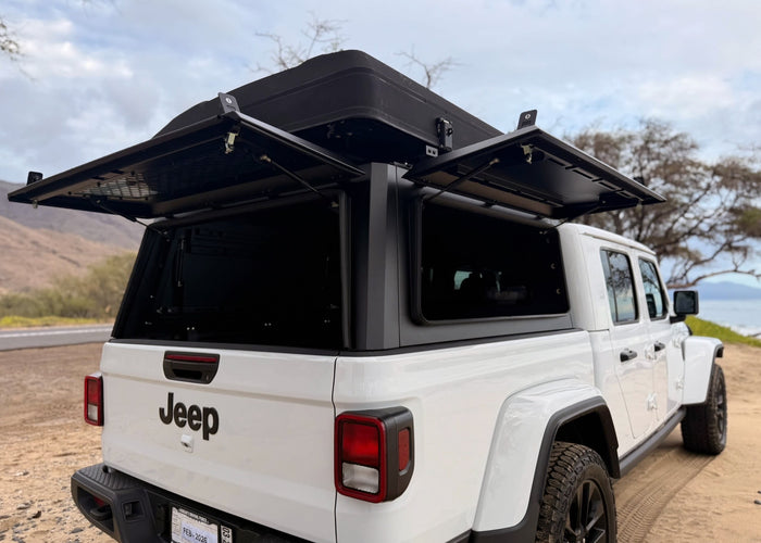 White Jeep Gladiator with open rooftop tent & camper shell, ready for your RV rental adventure.