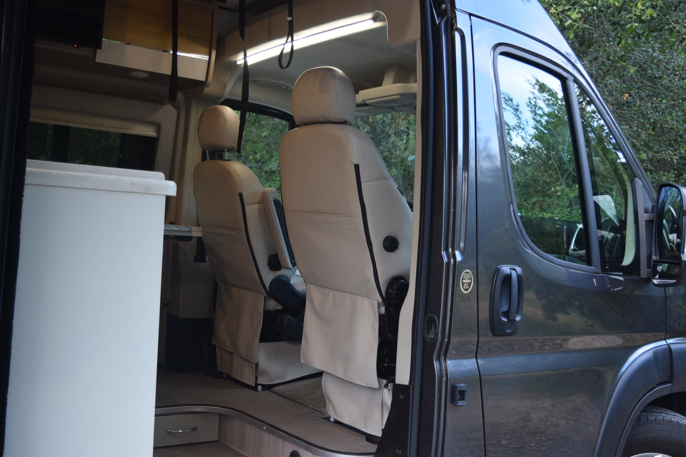 Inside an RV rental: Comfortable captain's chairs in a modern camper van's front cabin.