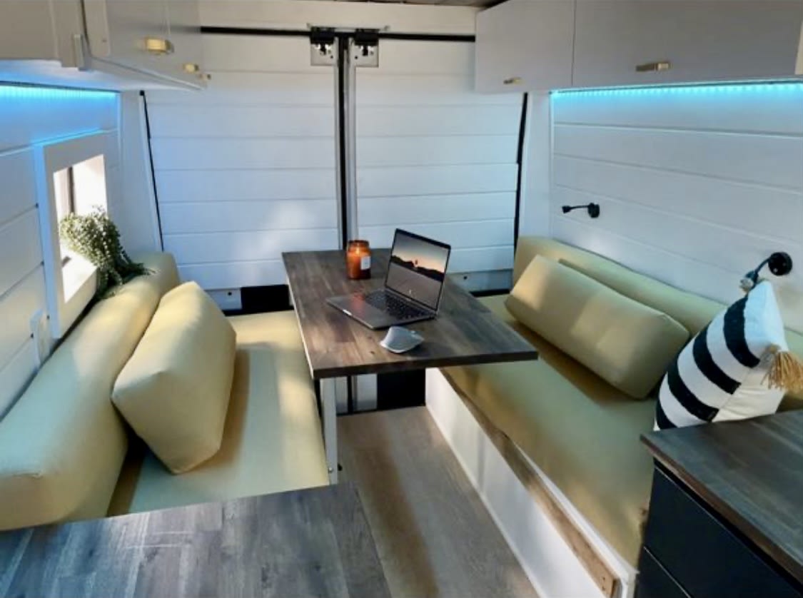 enjoying nature views & a picnic area from their van.|Pet-friendly RV rental interior: two dogs relaxing on custom beds