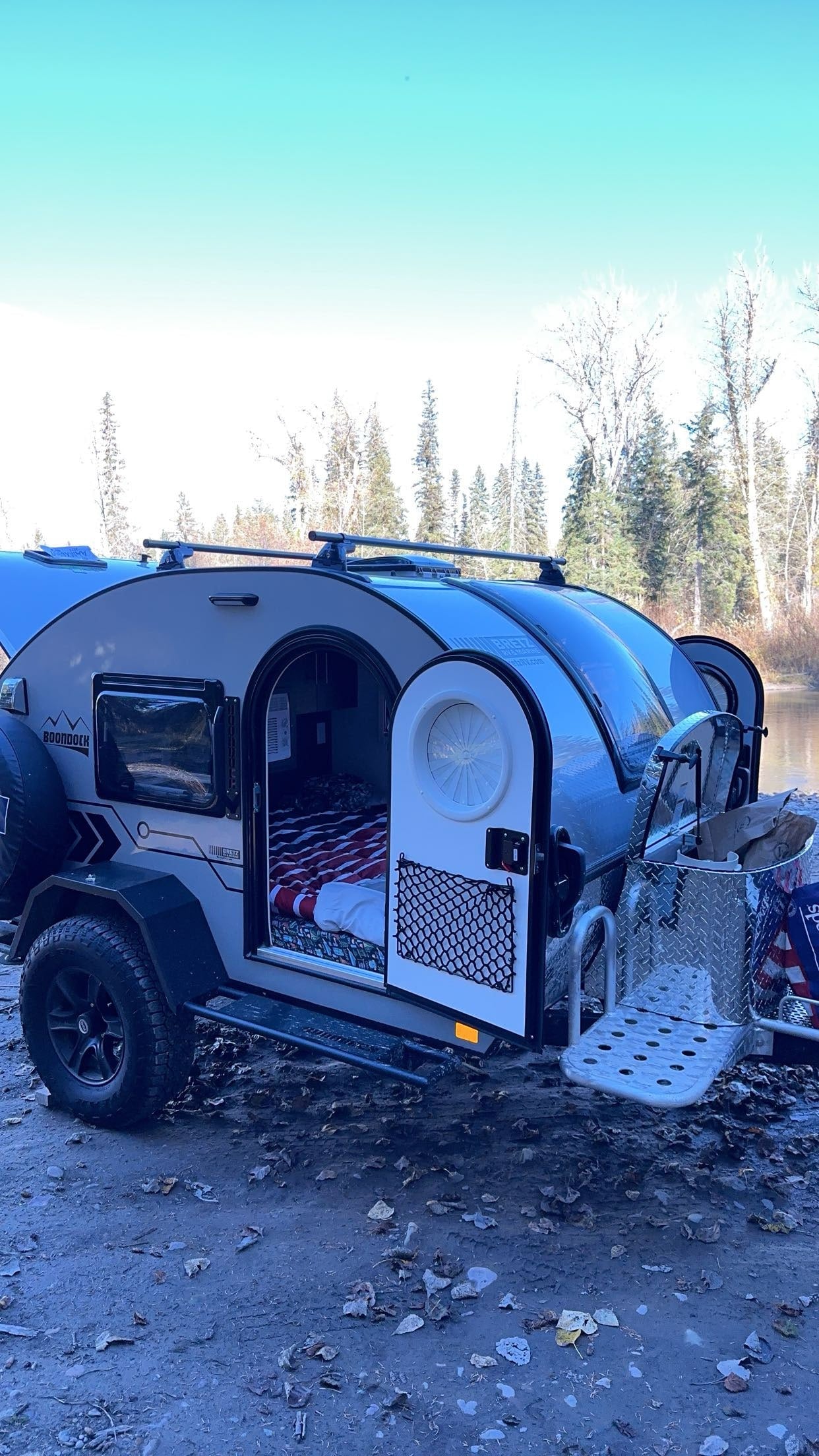 rear hatch open for adventure.|Teardrop RV rental parked by a peaceful river at sunset