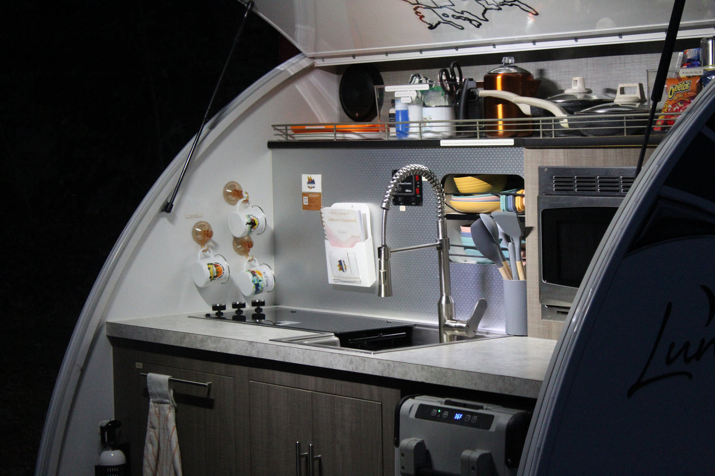 Compact RV rental kitchen with stove, sink, microwave & fridge. Perfect for camping adventures and road trips.