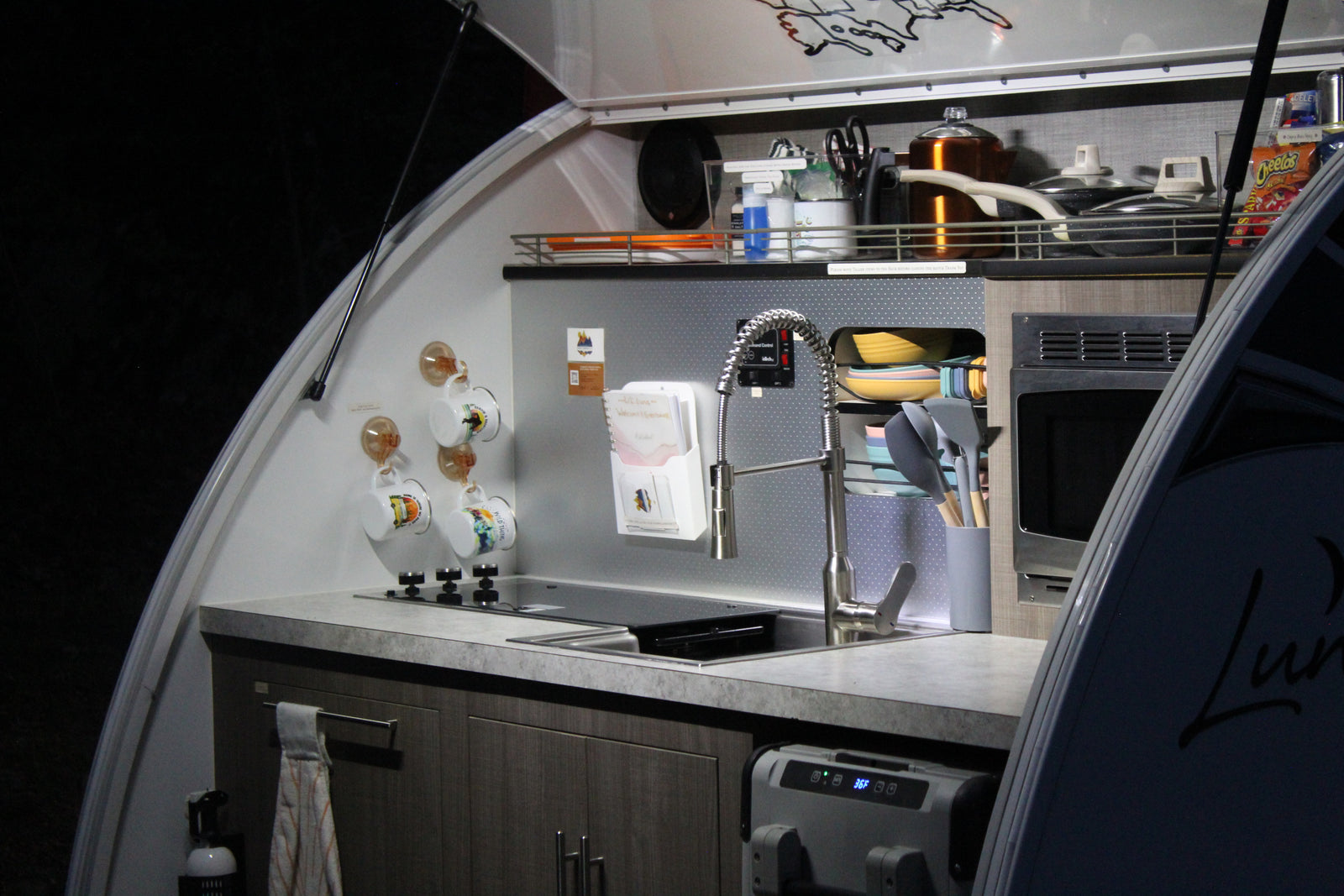 Compact RV rental kitchen with stove, sink, microwave & fridge. Perfect for camping adventures and road trips.