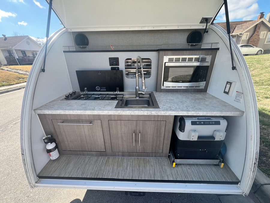 reading a book while enjoying a beautiful lake and forest view from inside.|White Luna teardrop camper RV rental
