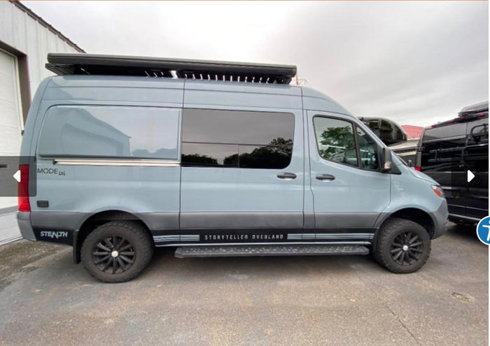 equipped for adventure with a side ladder and roof rack.|Light blue-grey Storyteller Overland Mode 4x4 camper van