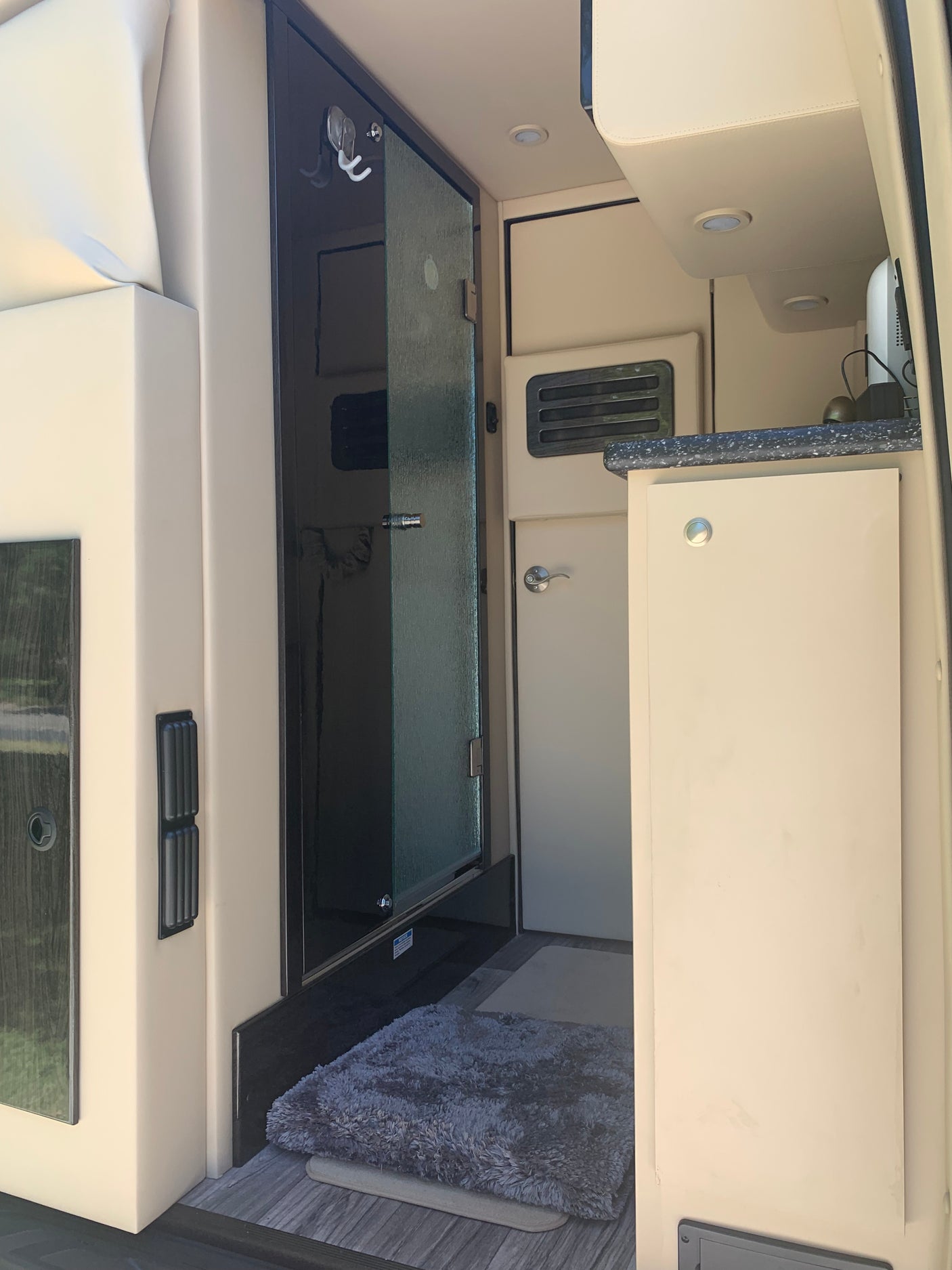 Modern rv rental interior: A compact, efficient space with a bathroom, small kitchen counter, and storage, perfect for travelers.