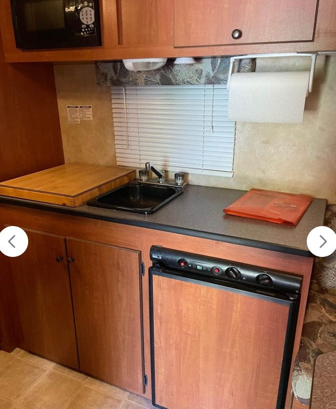 revealing a compact interior kitchen. Ready for travel!|RV rental kitchen: compact space with microwave
