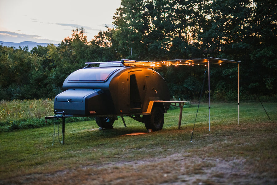 Scenic RV rental: This cozy teardrop camper with illuminated awning and table offers perfect outdoor escape.|Topo 2 RV rental: This compact camping trailer reveals an equipped outdoor kitchen with sink