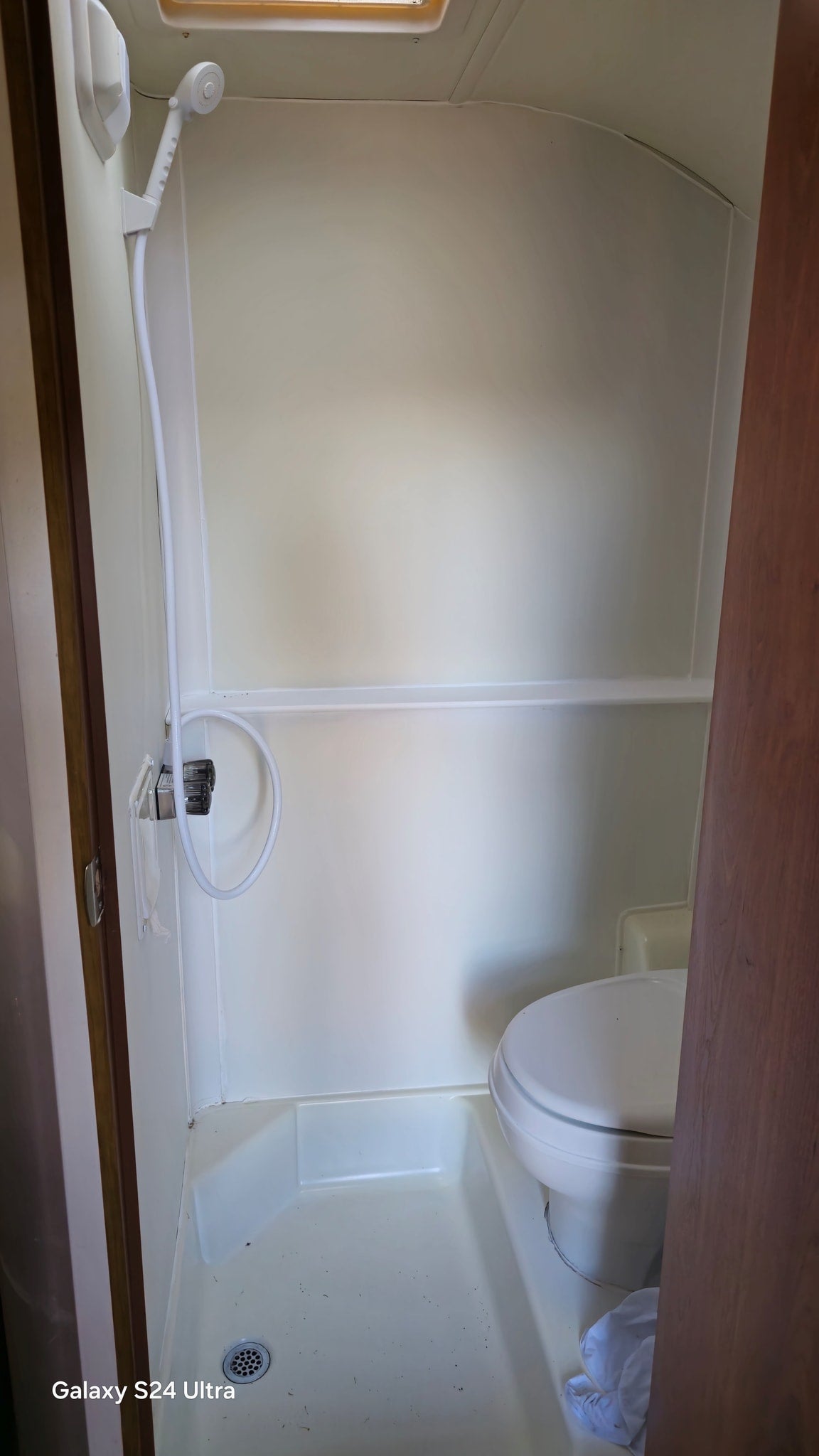 Step inside this RV rental's compact wet bath featuring a shower, toilet, and overhead skylight.