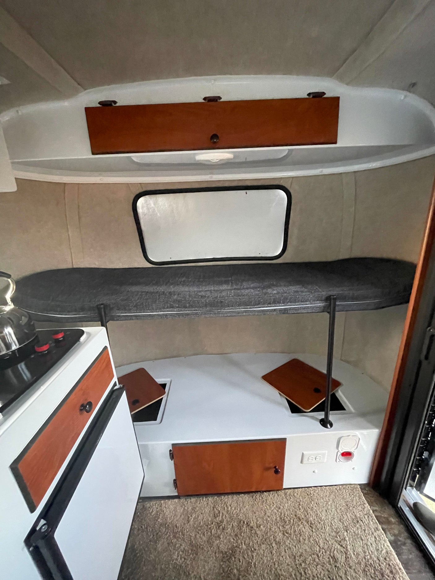 Compact RV rental interior featuring bunk bed, kitchenette, and clever storage. Ideal for camper adventures.