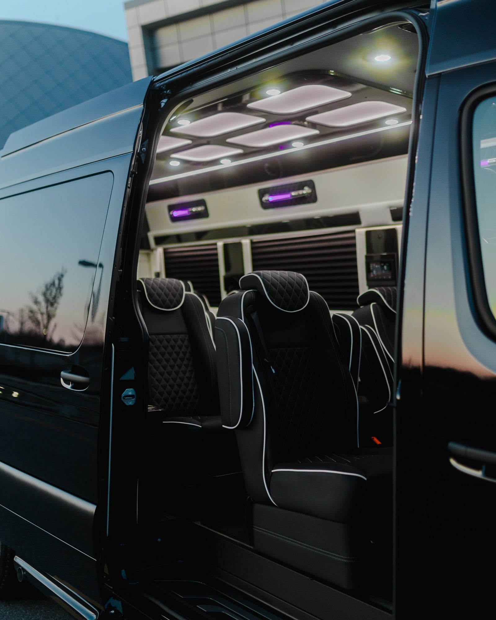Spacious luxury RV rental van interior with black quilted leather seats and modern ceiling lighting for comfortable travel.