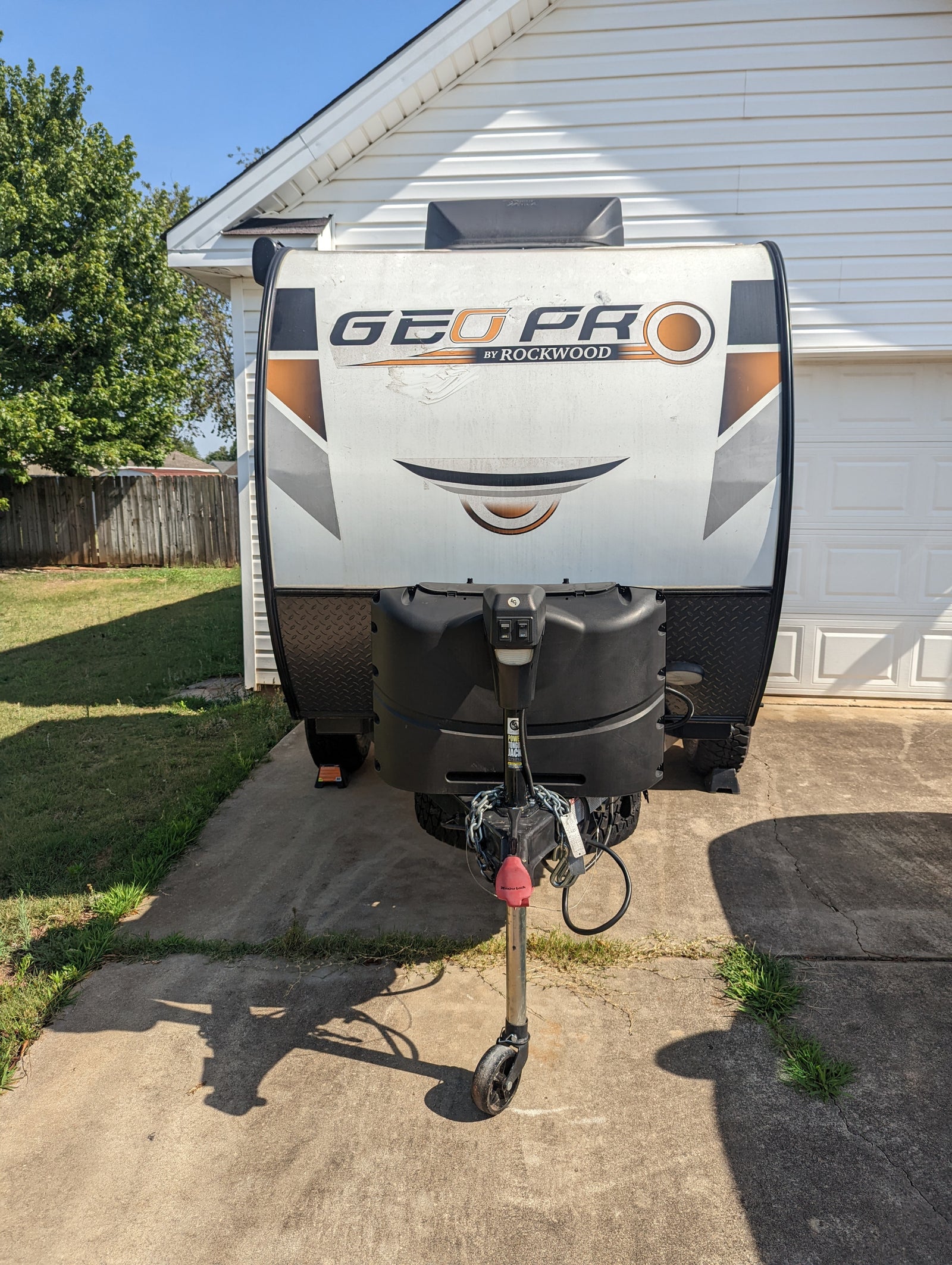 Front view of a white & black Geo Pro travel trailer parked on a driveway, ready for your next rv rental or camping trip.