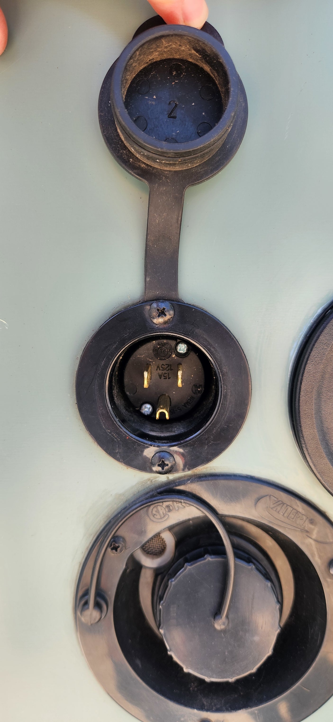 15A 125V electrical shore power outlet on an **RV rental**, with other utility hookups below it.
