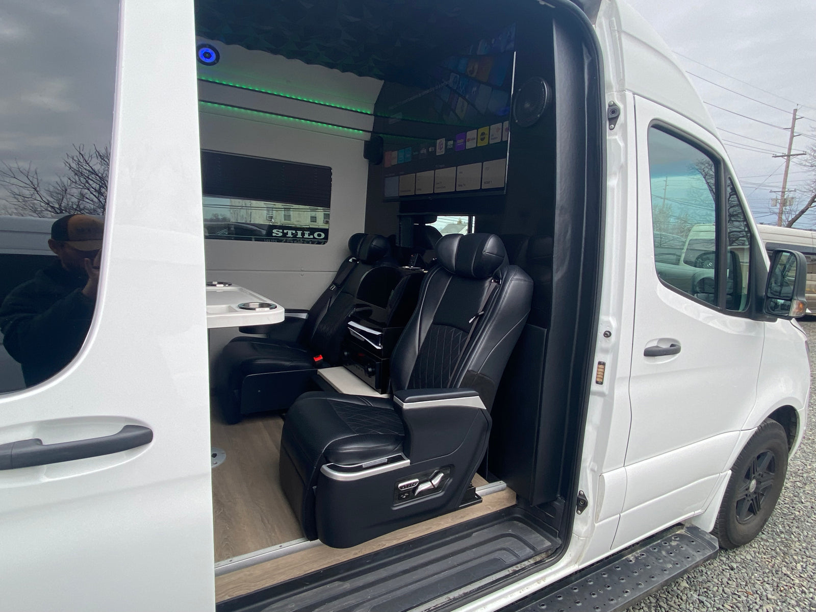 Experience luxury RV rental: custom van interior featuring executive seats, ambient lighting, and entertainment screen.