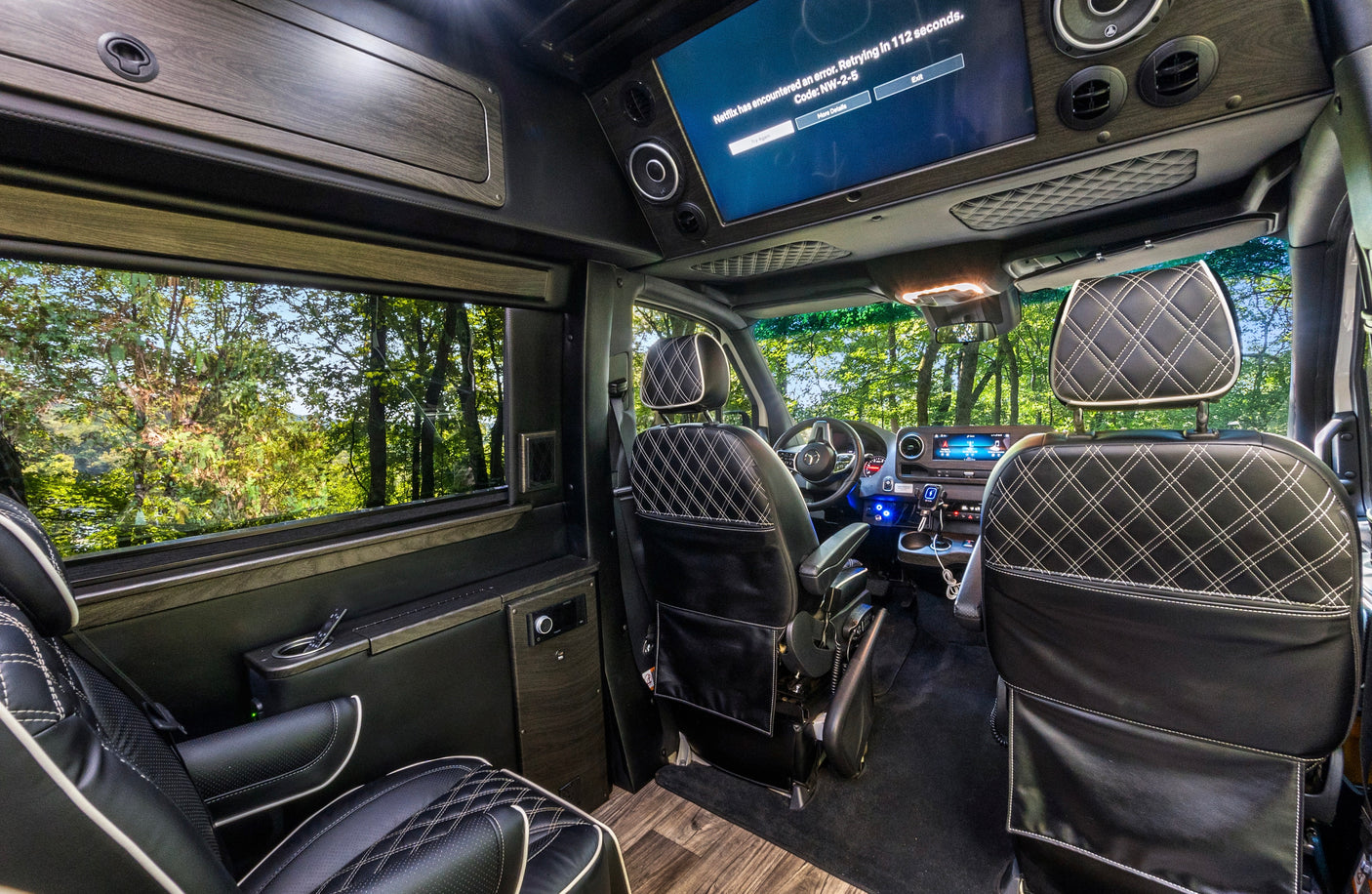Luxury rv rental interior with plush quilted seats, wood trim, and a screen displaying a Netflix error. Perfect for travel comfort.