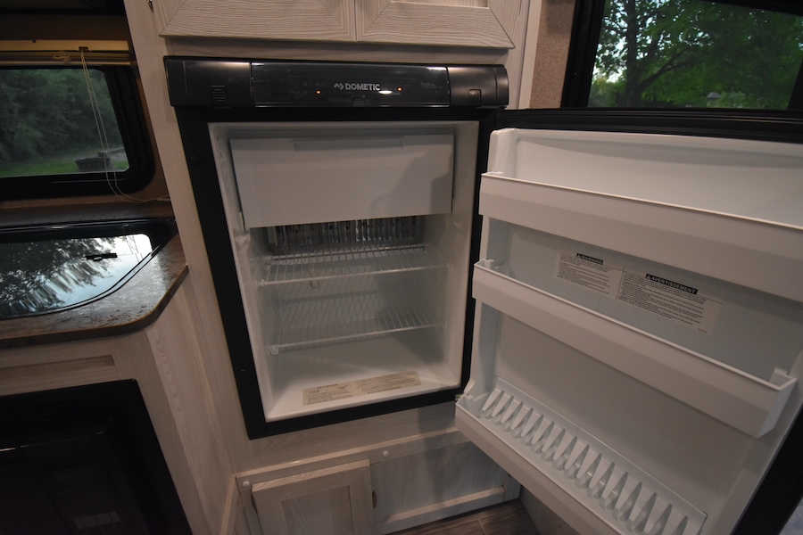 Clean, empty Dometic RV refrigerator with open door, showing shelves and freezer, in an RV rental.