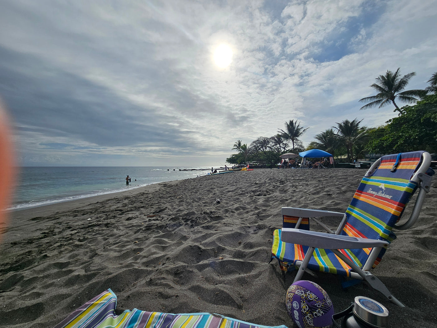 Sunny black sand beach day. Colorful chair by the ocean, a perfect stop during an RV rental trip.