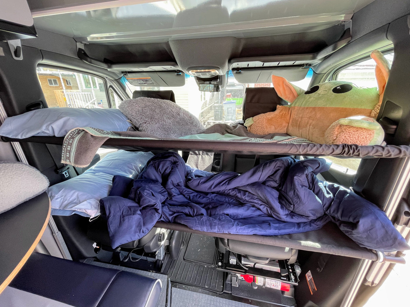 Cozy RV rental interior featuring two bunk beds with bedding, including a Grogu plushie on the top bunk.