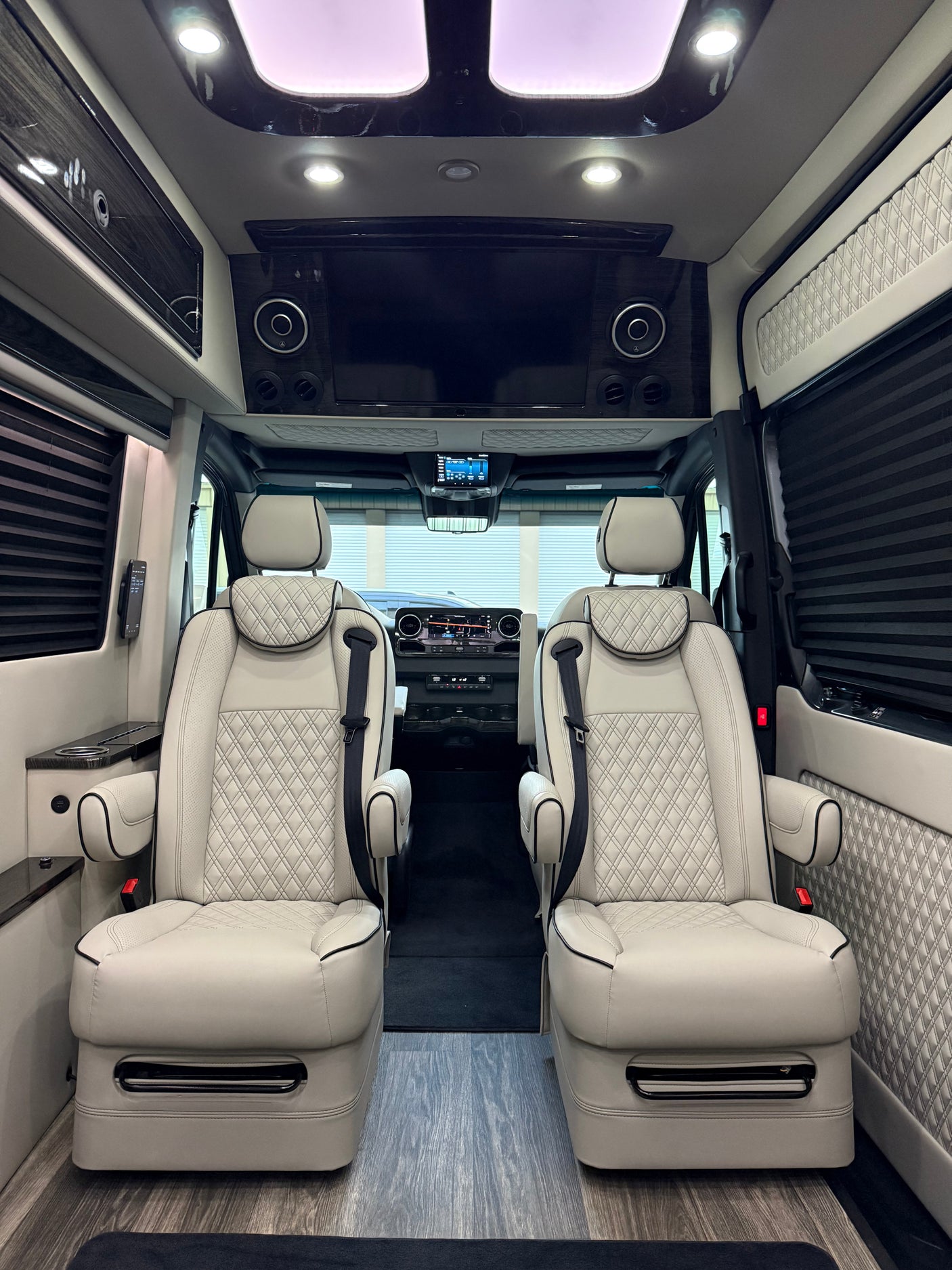 complete with an LG smart TV & plush seating.|Luxurious RV rental interior featuring two light-colored captain's chairs