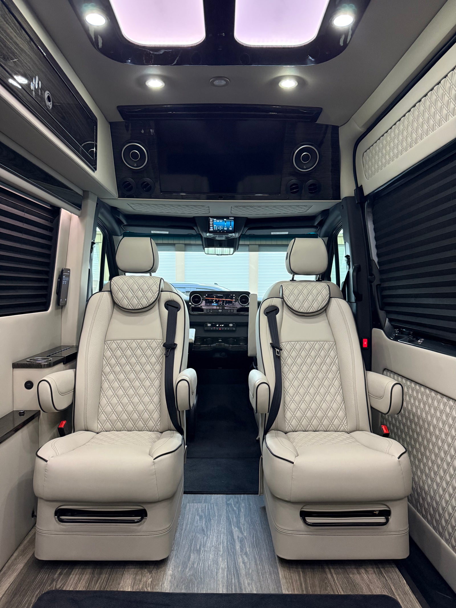complete with an LG smart TV & plush seating.|Luxurious RV rental interior featuring two light-colored captain's chairs