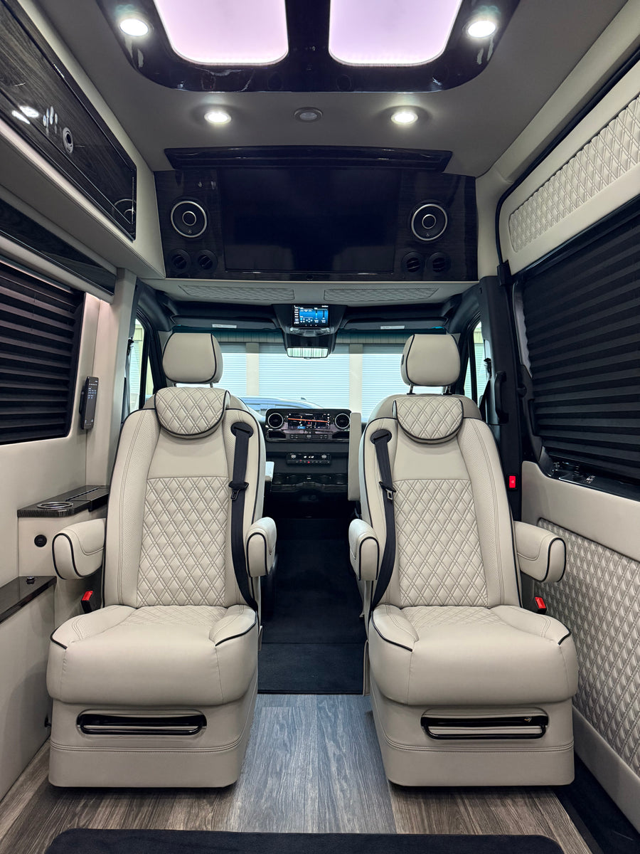 complete with an LG smart TV & plush seating.|Luxurious RV rental interior featuring two light-colored captain's chairs