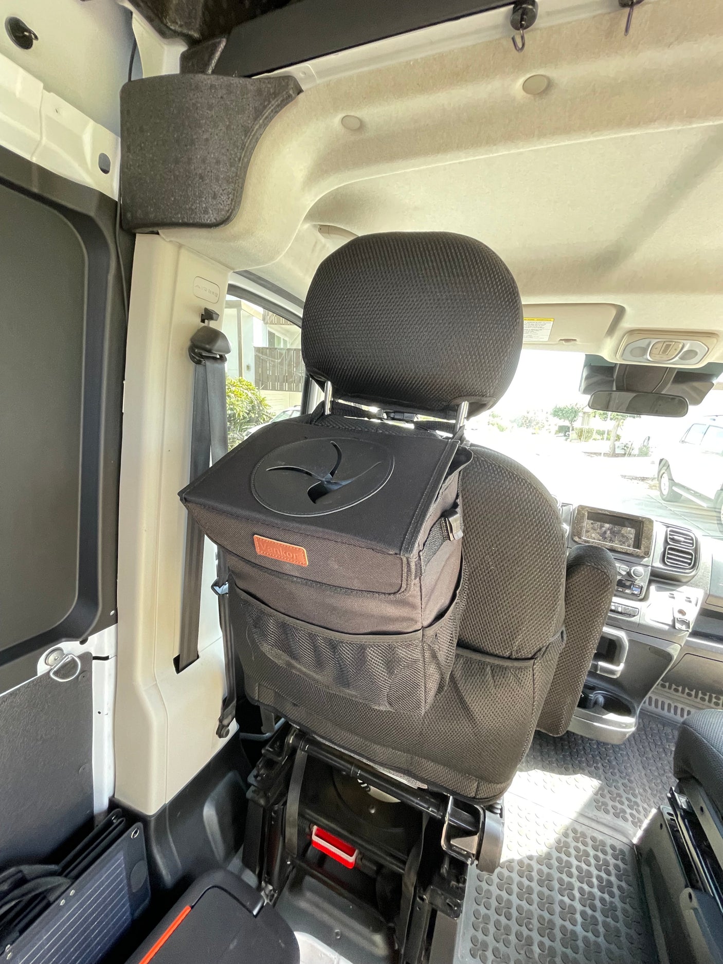 RV rental interior featuring a black car trash can securely mounted on the passenger seat headrest, promoting tidy travel.