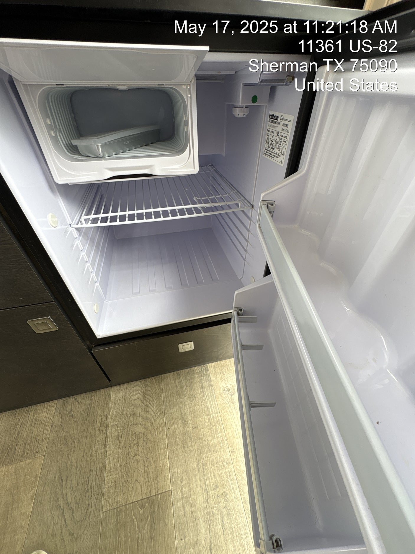 Clean, empty mini-fridge inside an rv rental, featuring a freezer compartment and door shelving.