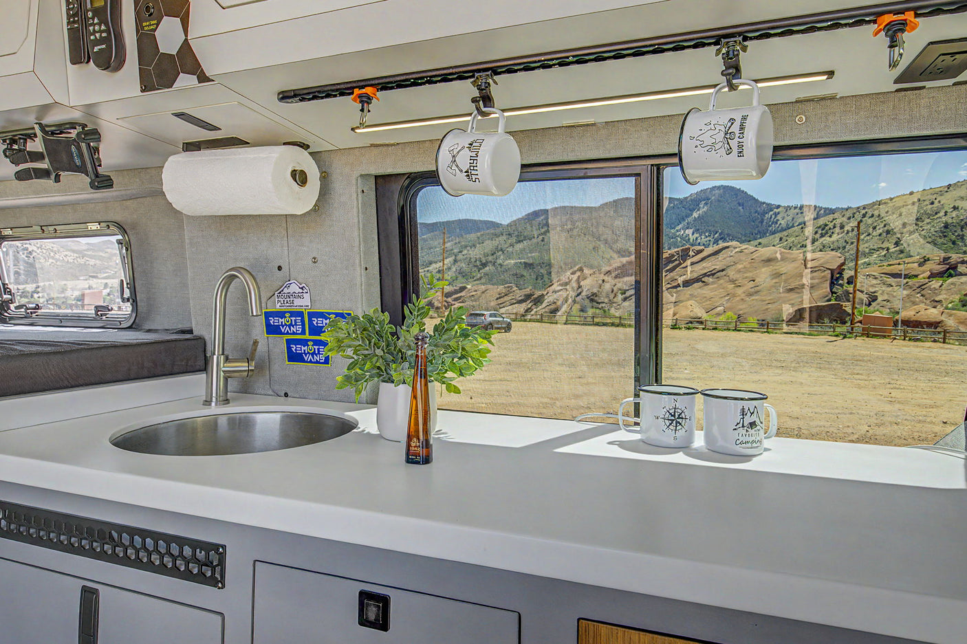 RV rental van life kitchen: sink, storage, and a stunning mountain view from the window. Perfect for adventures.
