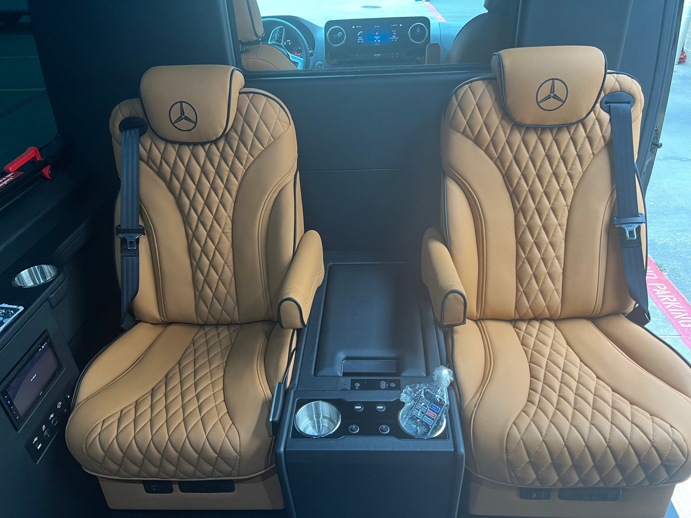 Plush tan leather Mercedes-Benz seating within a spacious RV rental, featuring diamond quilting and central console amenities.