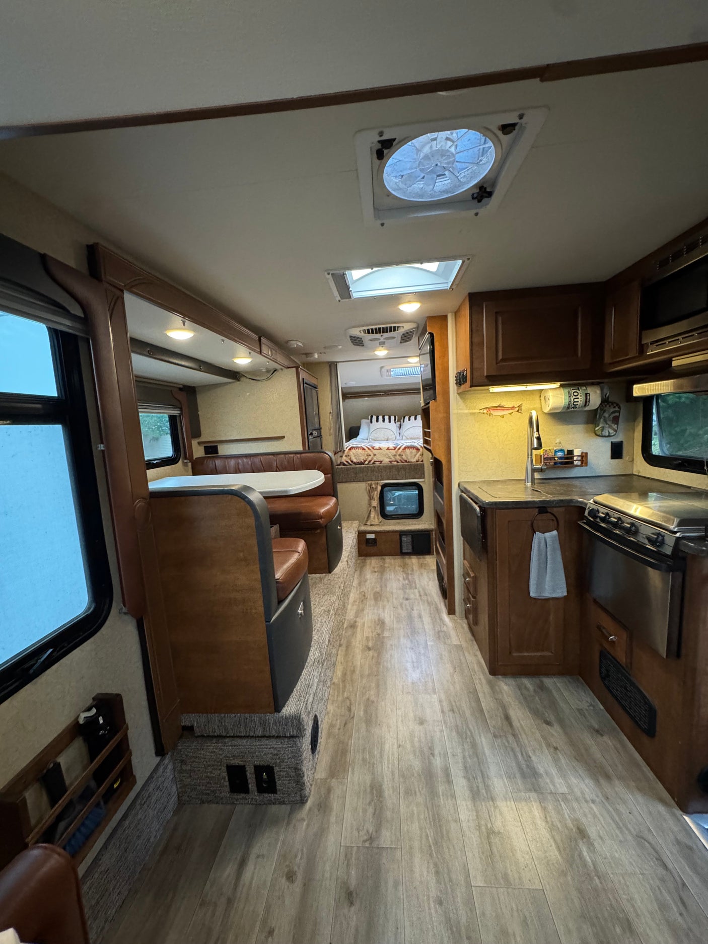 Interior of an RV rental: a spacious camper with a full kitchen, dining booth, and cozy bedroom. Ideal for travel.