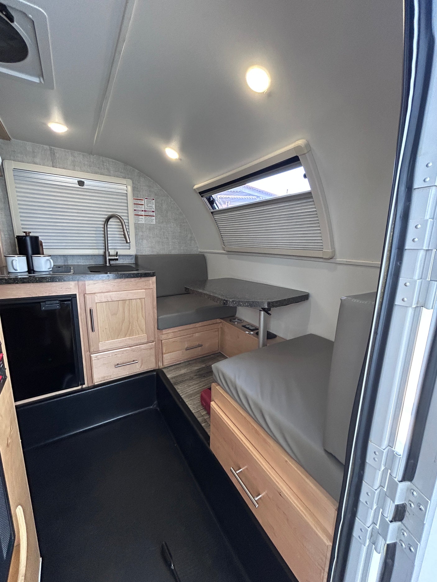 Compact RV rental interior featuring a modern kitchen, cozy dinette, and practical storage solutions.