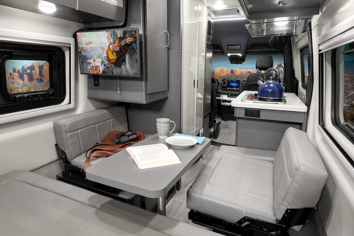 Experience an RV rental: a modern camper van interior featuring a comfortable dinette with TV and a full kitchenette.