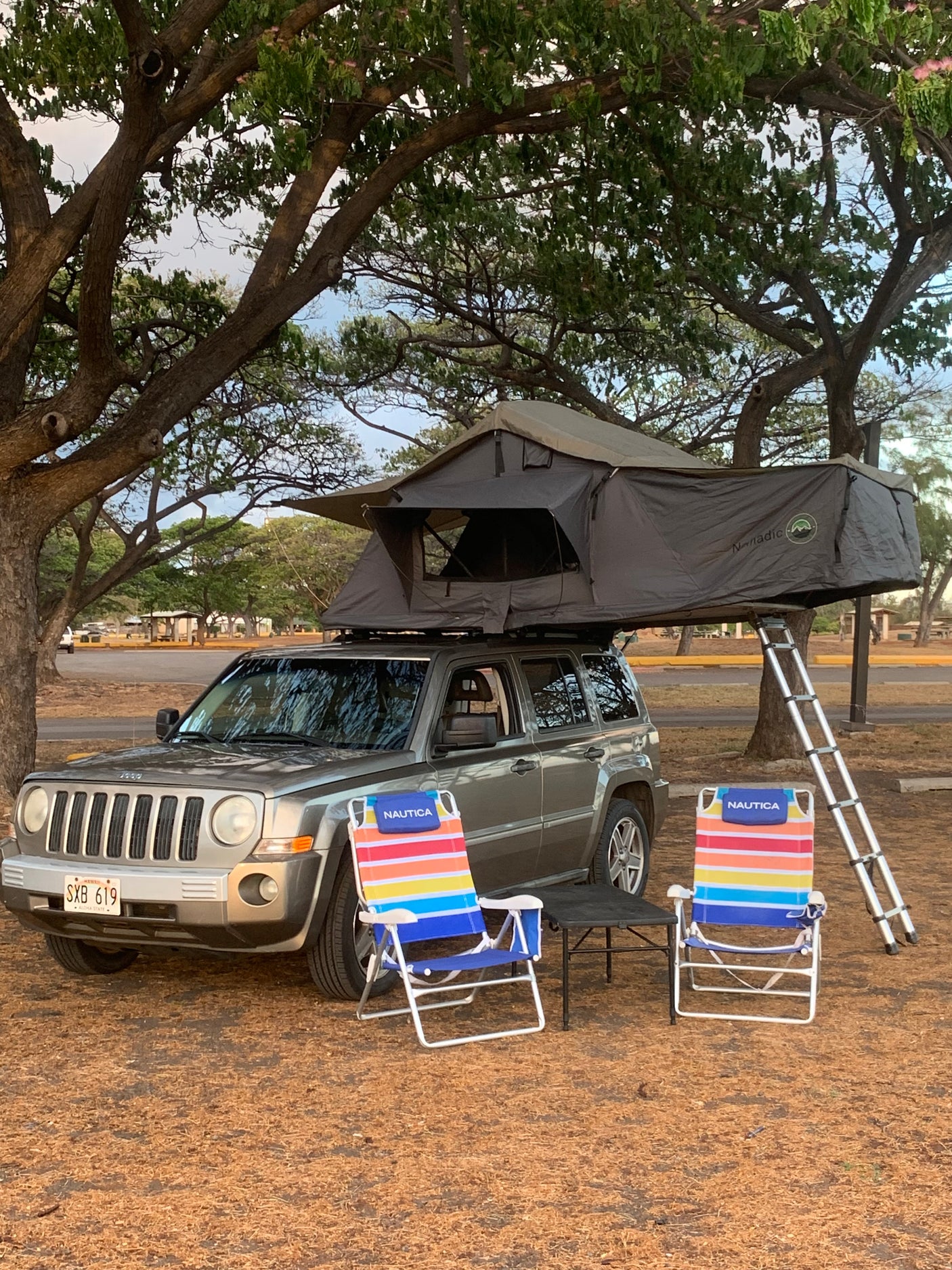 Hawaii camping: Jeep Patriot with a rooftop tent, chairs, and table. Perfect RV rental for your next adventure!