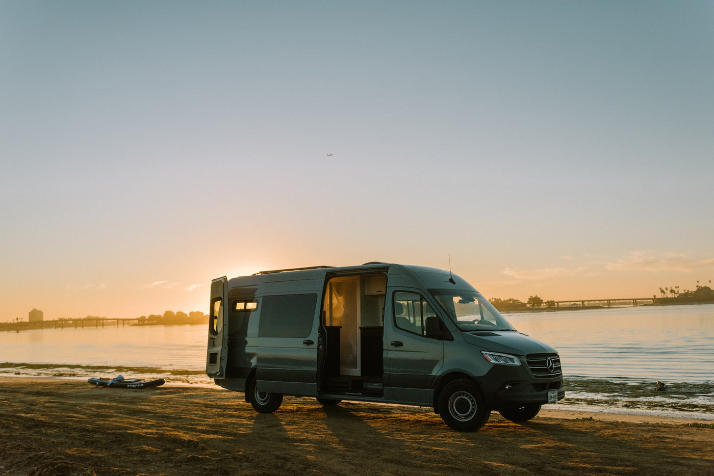 Scenic RV rental: A dark grey camper van parked on a sandy beach at sunset, with doors open, ready for adventure by the water. — photo 39