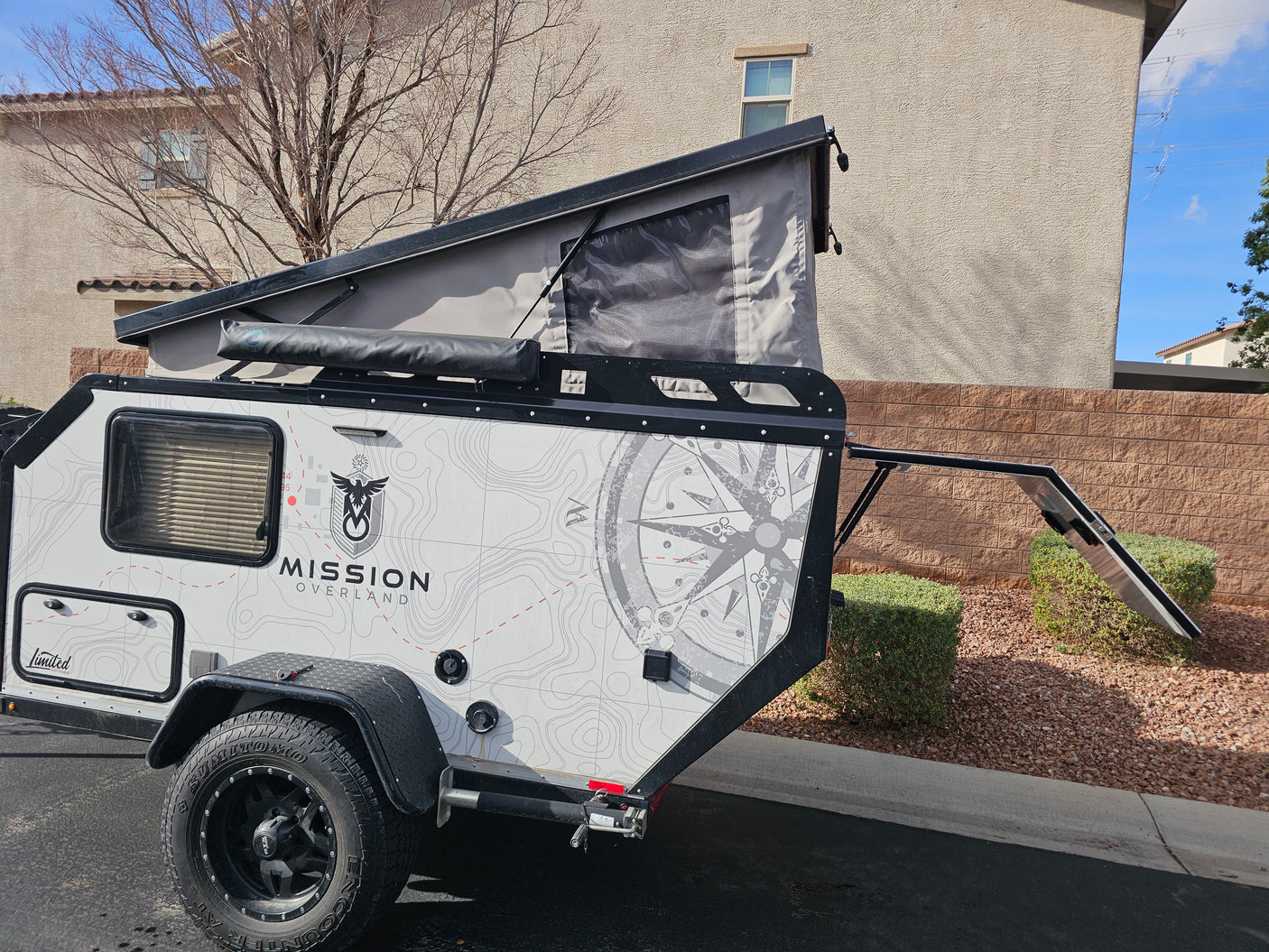 This Mission Overland off-road teardrop camper with a pop-up tent and custom graphics is ideal for an RV rental, camping, or overland journey.