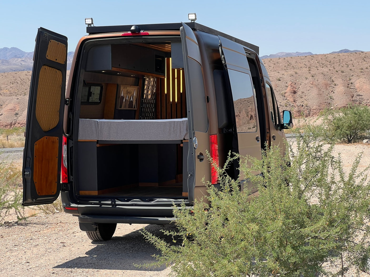 next to a comfy bed.|RV rental interior features a cozy bed
