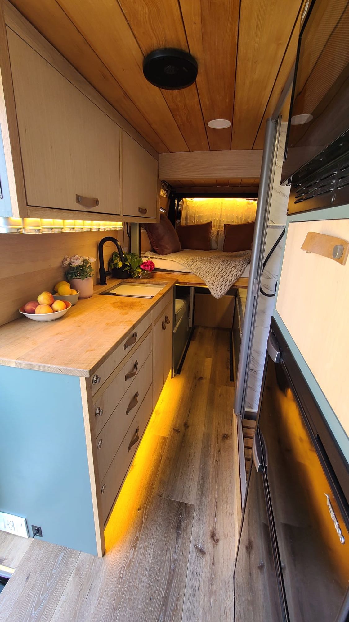 featuring a comfortable bed and compact kitchen area with a sink.|Step inside this RV rental's clever shower/toilet. Compact design — photo 10