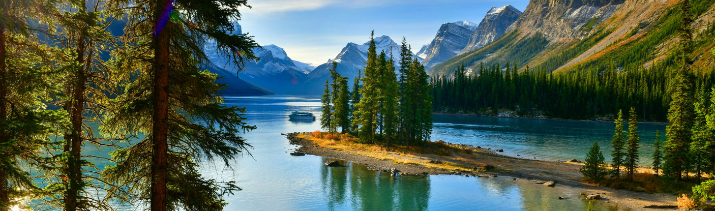 Experience this majestic mountain lake panorama framed by dense forests, with a boat on calm waters. Ideal RV rental adventure.