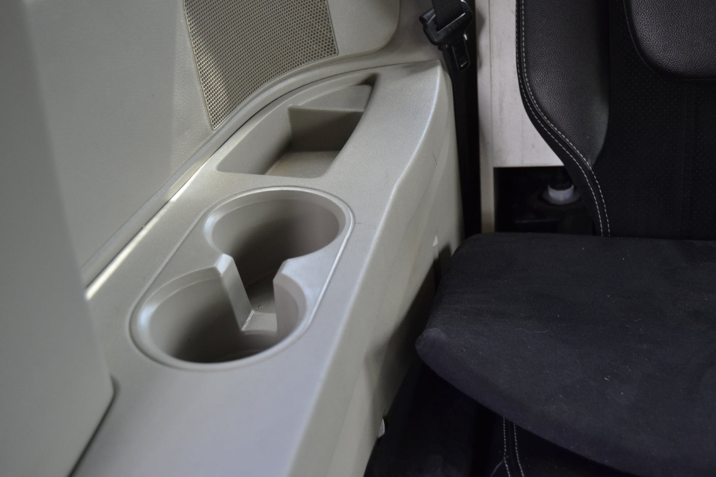 RV rental interior showing a light-colored console with cup holders, storage, and a speaker, next to a black seat.