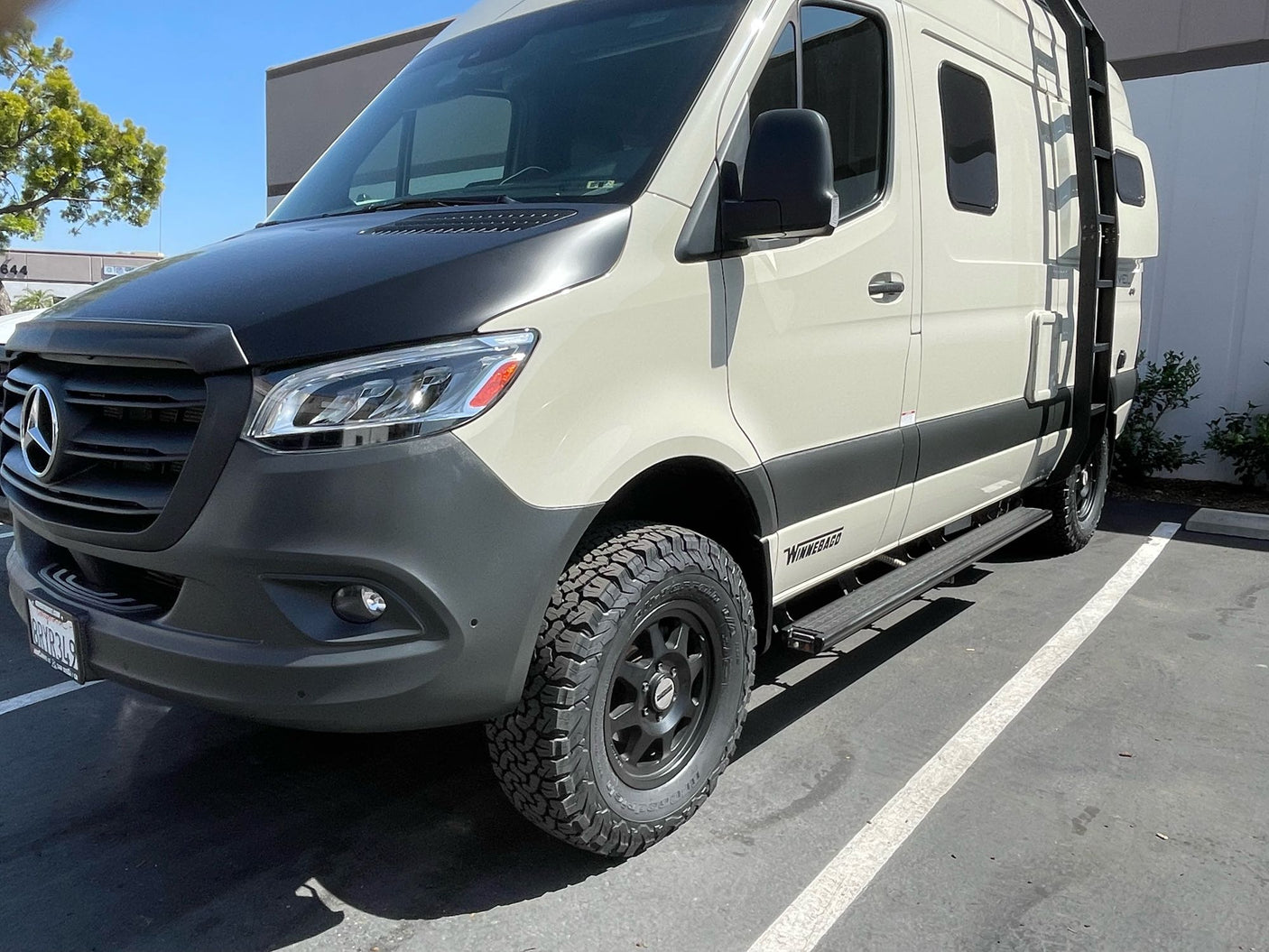 Adventure-ready Mercedes-Benz Sprinter RV rental with off-road tires, featuring a two-tone exterior and ladder.
