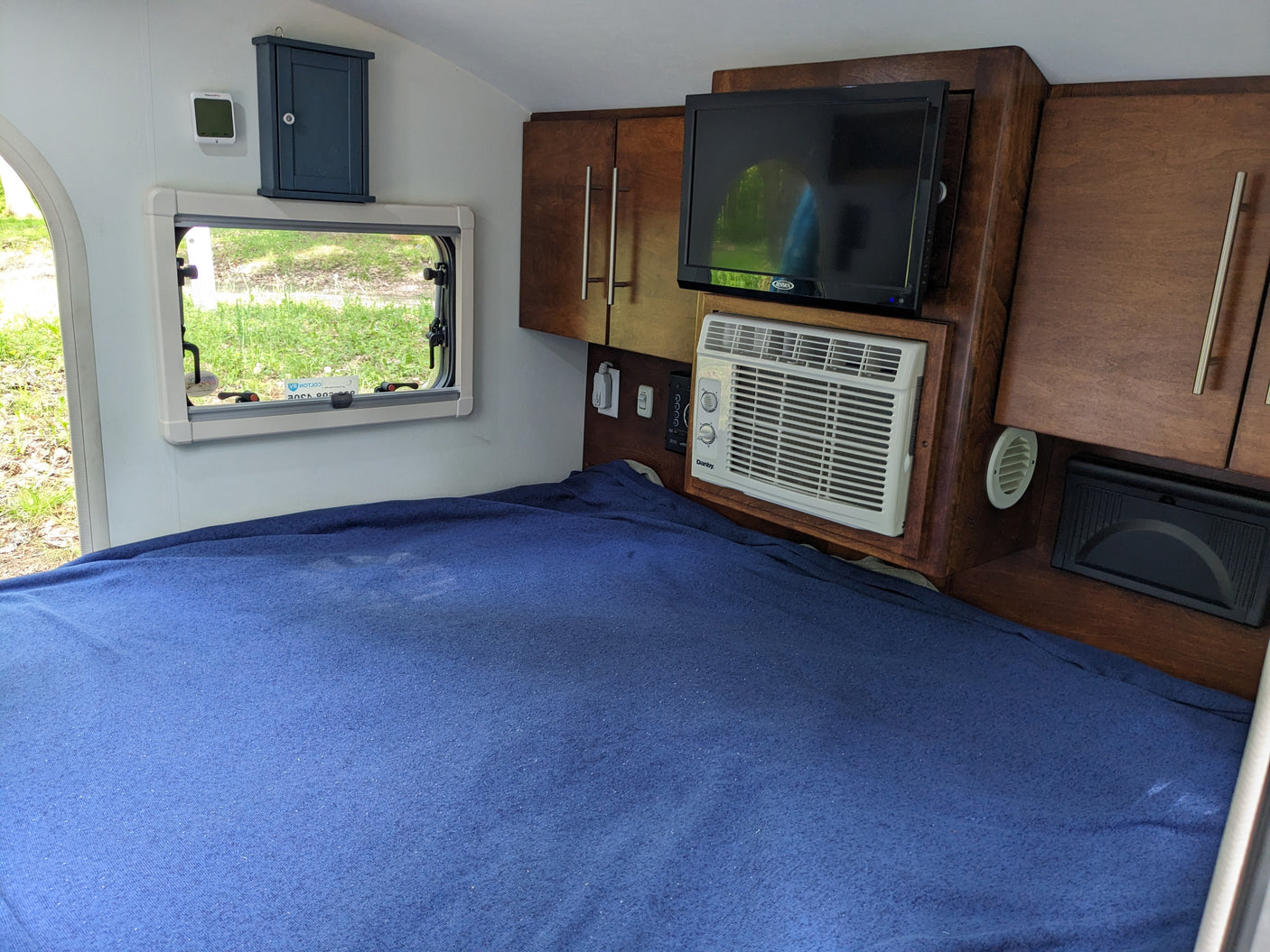 and fridge in a forest campsite.|Explore a convenient RV rental outdoor kitchen! Features include a sink