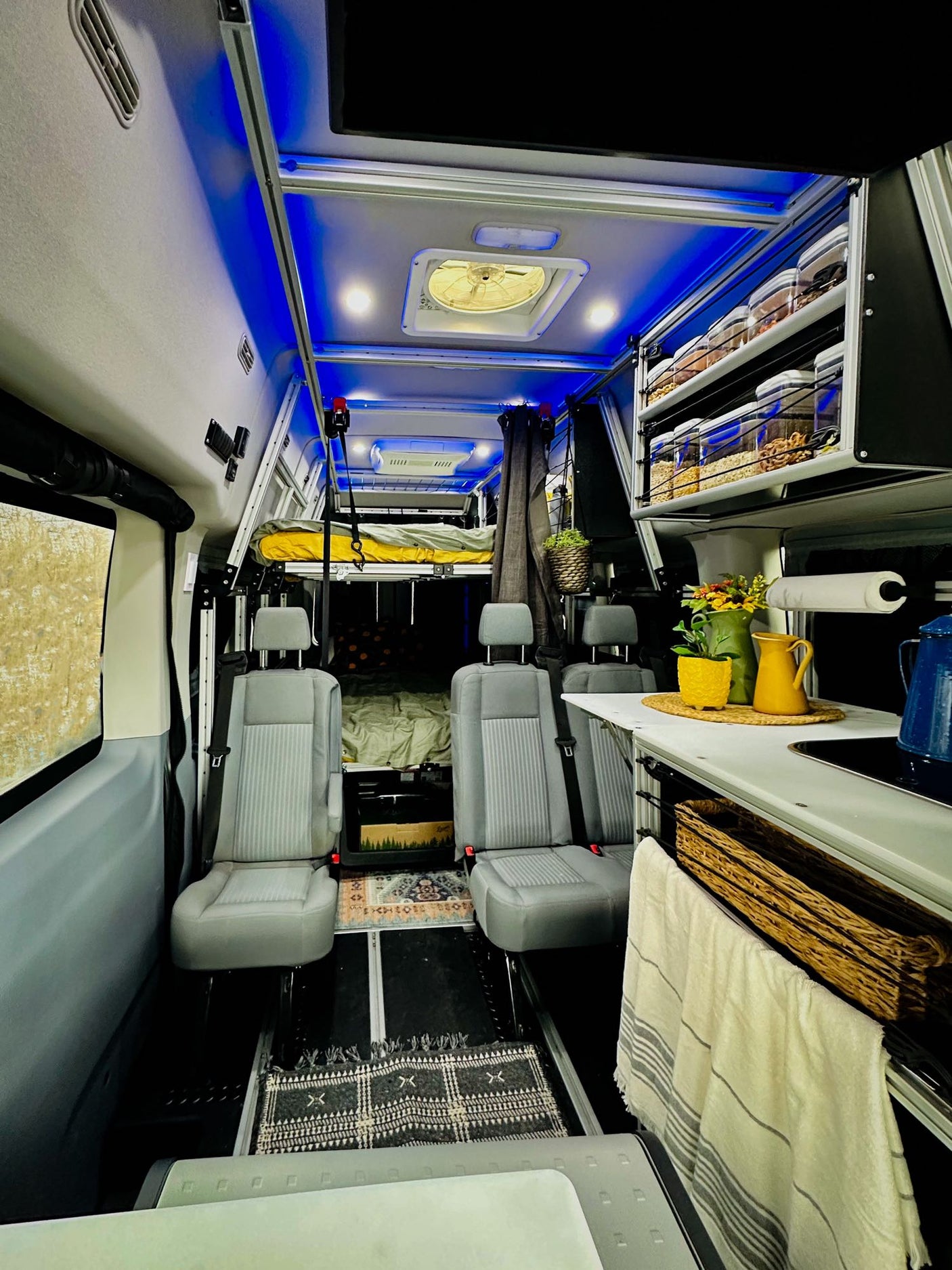 and a colorful rug.|Cozy RV rental interior: A woman reads on a modular bed in a camper van