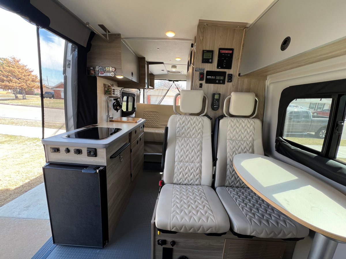 Modern RV rental interior with bright kitchen, quilted swivel seats, table, and storage. Ready for adventure. — photo 5