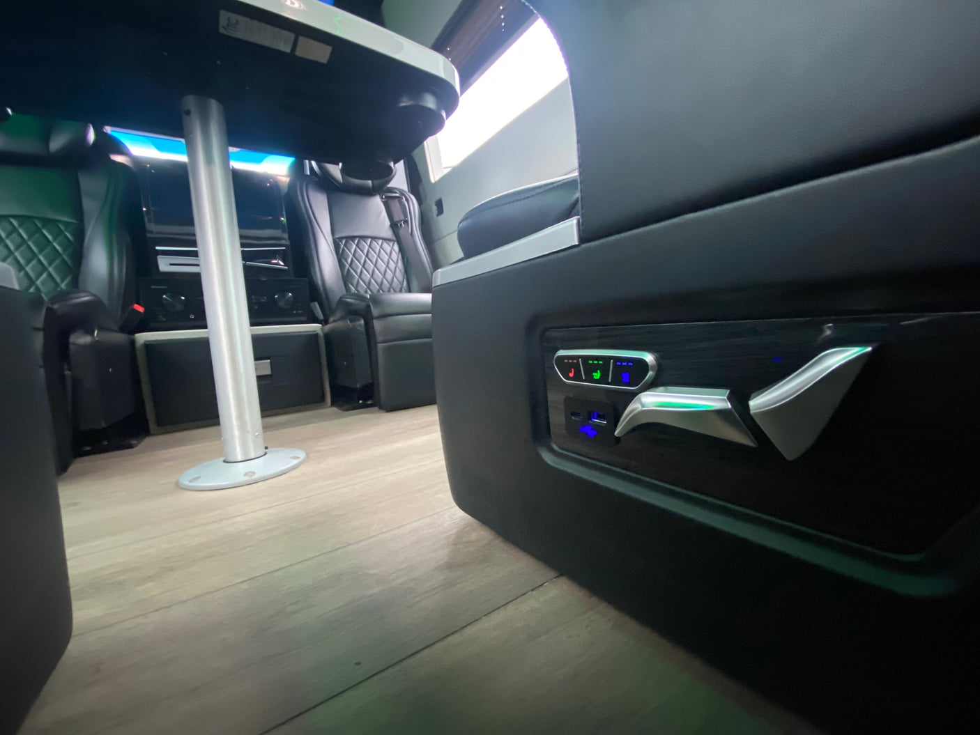 Luxury RV rental interior with illuminated seat controls, quilted seating, and a dining table.