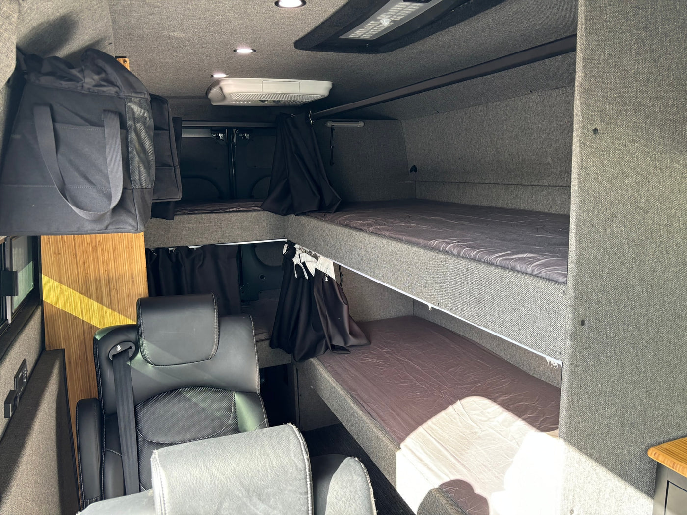 Inside this RV rental: modern camper van interior featuring bunk beds, swivel seats, overhead AC, and storage. — photo 5