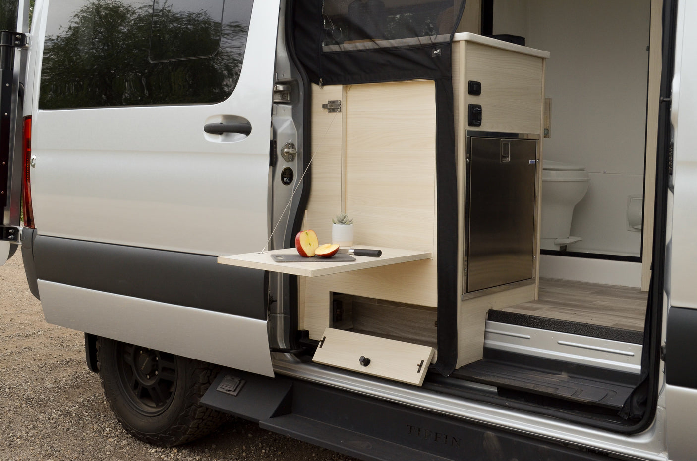 This rv rental showcases a modern camper van with an outdoor prep table, fridge, and compact bathroom setup for your journeys.